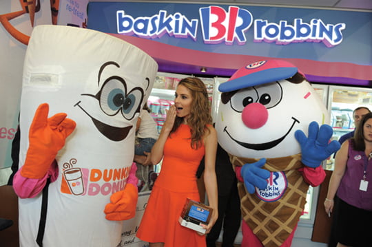 IMAGE DISTRIBUTED FOR DUNKIN' BRANDS - In this photo released on Tuesday, Oct. 9, 2012, "Extra" host and former Dunkin' Donuts crew member Maria Menounos joins mascots Cuppy and Coney to celebrate the launch of the first Dunkin' Donuts K-Cup packs at a Baskin-Robbins shop in Burbank, Calif. Menounos joined Dunkin' Brands CEO Nigel Travis to give away free boxes of Dunkin' K-Cups, which are available exclusively at participating Baskin-Robbins shops throughout California, to the first 31 guests. (Photo by Jordan Strauss/Invision for Dunkin' Brands/AP Images)