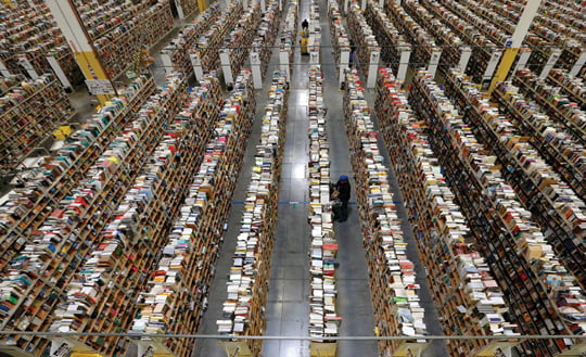 FILE - In this Monday, Dec. 2, 2013, file photo, an Amazon.com employee stocks products along one of the many miles of aisles at an Amazon.com Fulfillment Center in Phoenix. Holiday sales jobs are now likelier to be in warehouses and trucks than in retail stores. Amazon alone planned to hire 20,000 more holiday workers this year, according to the personnel firm Challenger, Gray & Christmas.  (AP Photo/Ross D. Franklin, File)