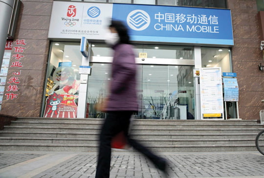 epa01294988 A woman walks past a China Mobile branch in Shanghai, China, 24 March  2008. The world's largest mobile phone service provider, posted strong growth across the board in subscribers, revenue, net profit, new music service members and instant messaging users, the company reported Wednesday. The company added 68.1 million new subscribers last year, nearly half from rural areas of China, operating revenue rose 20.9 percent year-over-year to 356.96 billion RMB (Euro 35.6 billion), while net profit increased 31.9 percent to 87.06 billion RMB (Euro 8.7 billion).  EPA/QILAI SHEN