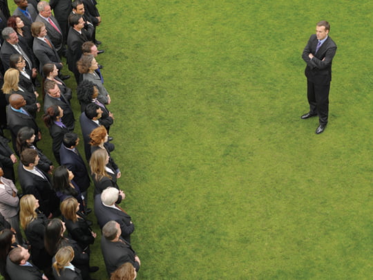 Business man facing large group of business people in formation, elevated view
