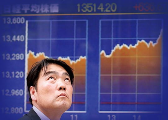 FILE - In this June 10, 2013 file photo, a man looks up by the day's chart of Tokyo's Nikkei 225, the regional heavyweight, that soared 636.67 points, or 4.94 percent, to 13,514.20 in front of a securities firm in Tokyo. Japan's economy grew at a slower-than-expected rate of 2.6 percent last quarter, suggesting demand has been slow to pick up despite strong public spending and ultra-lax monetary policies. The data released Monday, Aug. 12, 2013 by the Cabinet Office show the strongest contribution to growth coming from public spending and exports, while private investment weakened. (AP Photo/Koji Sasahara, File)