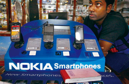 FILE- In this Thursday, June 14, 2012, file photo, an Indian shopkeeper selling Nokia mobile phones awaits customers in New Delhi, India.  Nokia's net loss more than tripled in the second quarter the company reported Thursday July 19, 2012.  (AP Photo/Tsering Topgyal, File)