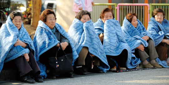 Elderly women wrapped themselves in blankets after evacuated a street after a powerful earthquake, in Tokoy Friday, March 11, 2011. A ferocious tsunami spawned by one of the largest earthquakes on record slammed Japan's eastern coasts Friday. (AP Photo/Kyodo News) MANDATORY CREDIT, NO LICENSING ALLOWED IN CHINA, HONG KONG, JAPAN, SOUTH KOREA AND FRANCE