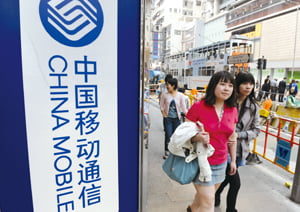  (FILES) In a file picture taken on March 18, 2010 people walk past a China Mobile outlet in Hong Kong. China Mobile, the world's largest mobile phone operator, said on August 19, 2010 that the "healthy momentum" of the Chinese economy had boosted its profits in the first half of the year.  The company earned 57.64 billion yuan (8.48 billion US dollars) in the six months ended June 30, up 4.2 percent from 55.33 billion yuan in the same period last year, it said.  AFP PHOTO/MIKE CLARKE
/2010-08-19 16:52:47/
