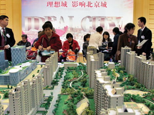  Potential buyers and sales staff stand around a model depicting high-rise apartments on a new estate block at the Beijing Property Trade Fair April 9, 2010. China's agency overseeing big state-owned businesses has received plans from 78 state companies spelling out how they intend to sell out of the nation's heady property market, a Chinese newspaper said on Friday.     REUTERS/David Gray      (CHINA - Tags: BUSINESS)/2010-04-09 16:30:15/
