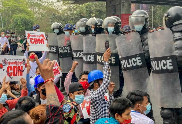 지난 18일(현지시간) 미얀마 최대도시 양곤에서 쿠데타 항의 시위대가 '시민 불복종 운동'(CDM·Civil Disobedience Movement)을 촉구하는 팻말을 들고 '세 손가락 경례'를 하며 진압경찰과 대치하고 있다. /사진=AP