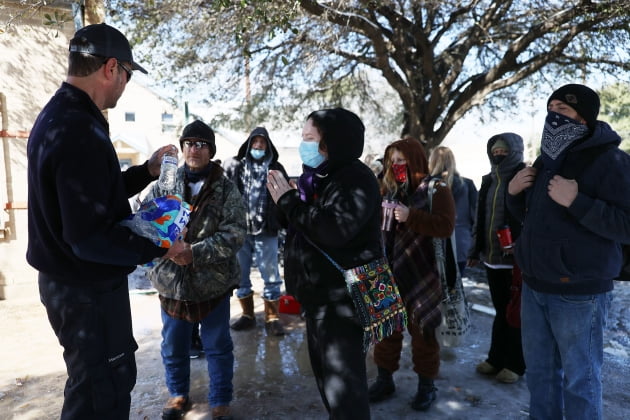 (사진) 오스틴재난구호네트워크의 자원 봉사자가 2월 19일 미국 텍사스주 오스틴에서 사람들에게 생수를 나눠주고 있다. /AFP 연합뉴스