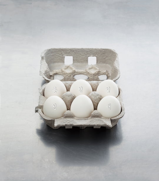 An egg carton with six white eggs on metallic surface.