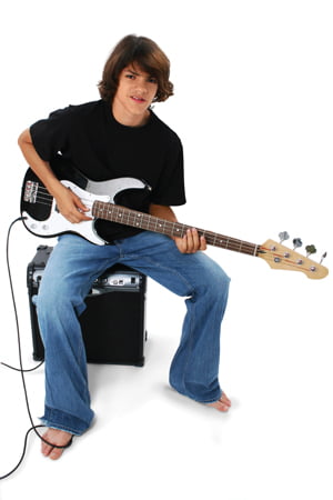 Boy With Black And White Bass Guitar Sitting On Amp. Shot in studio over white with the Canon 20D.