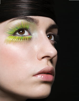 A woman wearing green false eyelashes