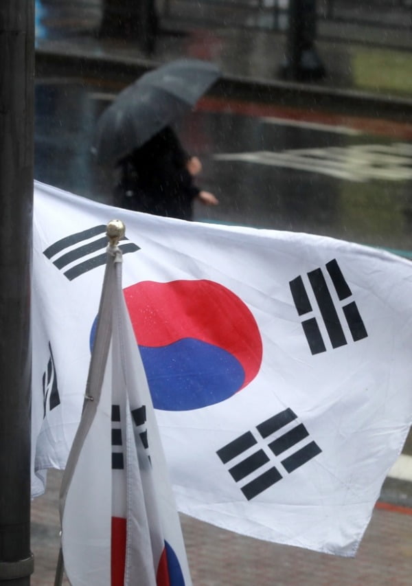 삼일절인 지난 1일 서울 종로구 일대에 걸린 태극기 뒤로 한 시민이 우산을 쓰고 걷고 있다. /사진=뉴스1