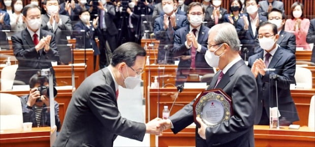 < 감사패 전달 > 김종인 국민의힘 비상대책위원장(오른쪽)이 8일 국회에서 열린 당 의원총회에서 주호영 원내대표에게서 감사패를 받은 뒤 주 원내대표와 악수하고 있다.  	 /국회사진기자단 