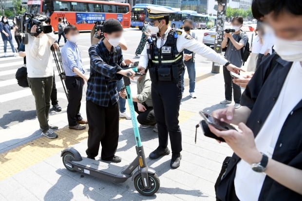 전동킥보드 등 개인형 이동장치(PM)의 이용 규제를 강화하는 개정 도로교통법 시행이 시작된 13일 오후 서울 마포구 홍대입구역 인근 인도에서 마포경찰서 경찰들이 전동킥보드를 이용하는 시민에게 재개정 관련 내용 홍보 및 계도를 하고 있다. 허문찬 기자