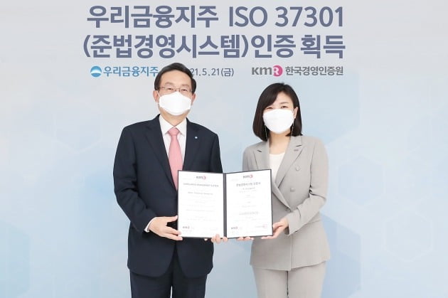 우리금융지주가 국내 금융권 최초로 준법경영시스템 국제표준(ISO 37301) 공식 인증을 받았다. 손태승 우리금융 회장(왼쪽)과 황은주 한국경영인증원장이 21일 서울 중구 우리금융 본사에서 인증서를 들어보이고 있다.  /우리금융 제공