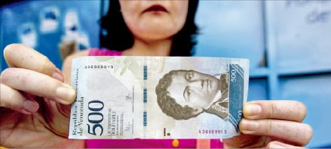 베네수엘라의 한 국민이 볼리바르 지폐를 들어 보이고 있다. 물가 급등 영향으로 이 화폐 가치는 계속 떨어지고 있다. /한경DB 