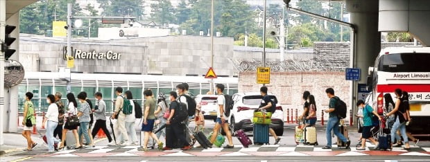 < 몰리는 관광객, 불안한 제주 > 여름 휴가철을 맞아 이동 인구가 늘면서 수도권의 코로나19 ‘4차 대유행’이 비수도권으로 확산될 조짐을 보이고 있다. 지난 10일 제주국제공항에 도착한 관광객들이 렌터카 주차장으로 이동하고 있다. 이달 들어서만 121명의 확진자가 나온 제주에선 면세점 폐쇄 등이 잇따랐다.   연합뉴스 