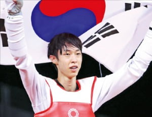 장준이 지난 24일 태권도 남자 58kg급 경기에서 동메달을 획득한 뒤 태극기를 들고 환호하고 있다. 뉴스1 