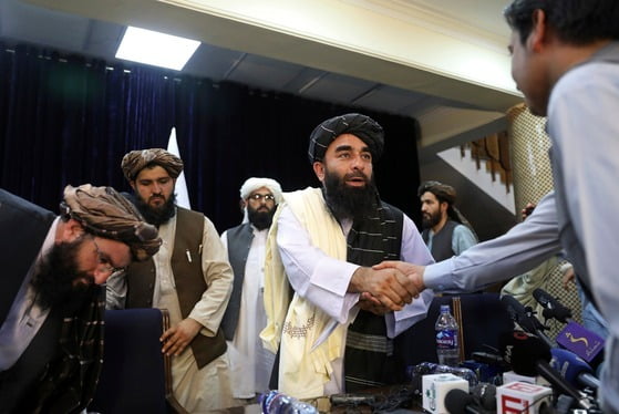 자비훌라 무자히드 탈레반 대변인이 외신 상대 기자회견을 마친 뒤 기자들과 악수하고 있다./ AP=연합뉴스
