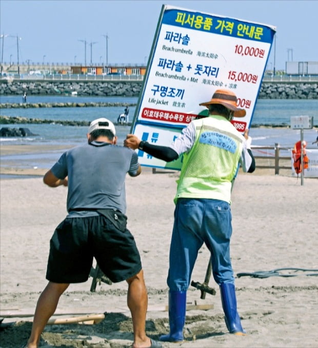 < 제주도 12개 해수욕장 모두 폐쇄 > 18일 제주도 관계자들이 제주시 이호해수욕장에서 해수욕 관련 용품 가격을 알리는 팻말을 철거하고 있다. 제주도는 이날부터 2주간 거리두기를 4단계로 격상하고 도내 12개 해수욕장을 모두 폐쇄했다.     /뉴스1 