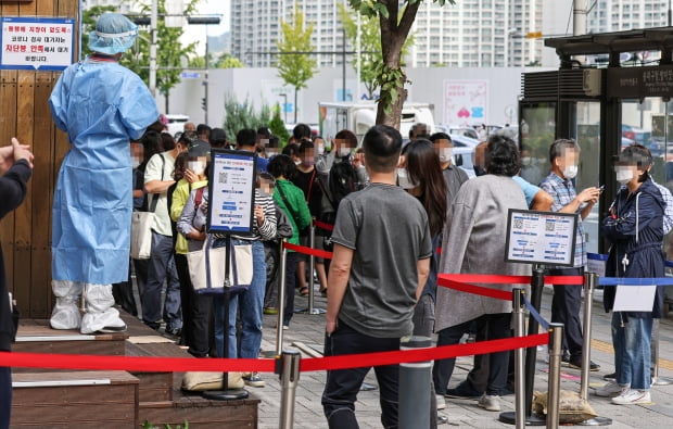 27일 오전 서울 송파구 송파구보건소 코로나19 선별진료소에서 한 관계자가 검사를 받기 위해 대기하고 있는 시민들을 바라보고 있다. 사진=연합뉴스