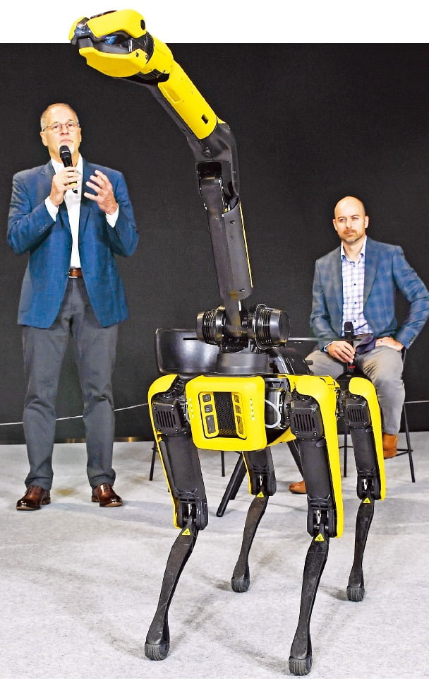 < 달라진 로봇개…움직이는 팔 생겼네 > 보스턴다이내믹스의 로버트 플레이터 최고경영자(CEO·왼쪽)와 애런 손더스 최고기술책임자(CTO)가 4족 보행 로봇 ‘스폿’에 움직이는 팔을 붙인 ‘스폿 암’을 시연하며 설명하고 있다. /현대차그룹  제공 