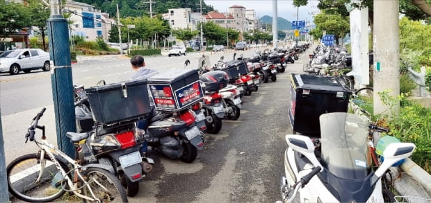 지난 10일 경남 거제시의 한 조선소 인근 도로에 협력업체 직원들이 퇴근 후 사용할 배달용 오토바이들이 세워져 있다.  조선사 협력업체 제공 