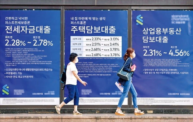 지난 2분기 가계·기업 등 민간부문 빚이 사상 처음 4300조원을 넘어섰다. 눈덩이처럼 불어난 빚이 소비와 투자를 가로막는 요인이 될 것이란 지적이다. 24일 시민들이 한 시중은행의 대출 광고판 앞을 지나가고 있다.  /김영우 기자 