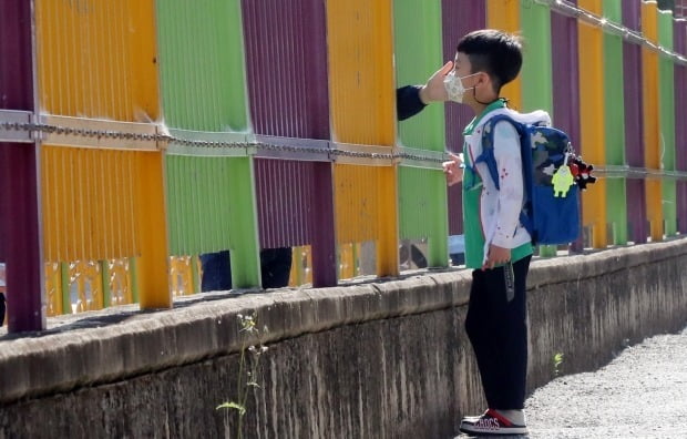 한 초등학교에서 등교하는 학생이 학교 담장 밖으로 지나는 엄마와 인사하고 있다. 사진은 기사와 연관없음 (사진=연합뉴스)