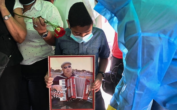 코로나19로 사망한 온두라스의 음악가 마카리오 메지아의 장례식에서 한 어린이가 그의 사진을 들고 있다. 사진=AFP