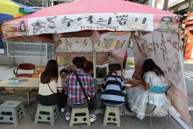 넷플릭스 한국 오리지널 시리즈 '오징어 게임'이 이레째 넷플릭스 전 세계 인기 순위 1위 자리를 지키고 있는 1일 오후 서울 종로구 대학로의 한 달고나 가게에서 시민들이 달고나를  하고 있다. [사진=뉴스1]