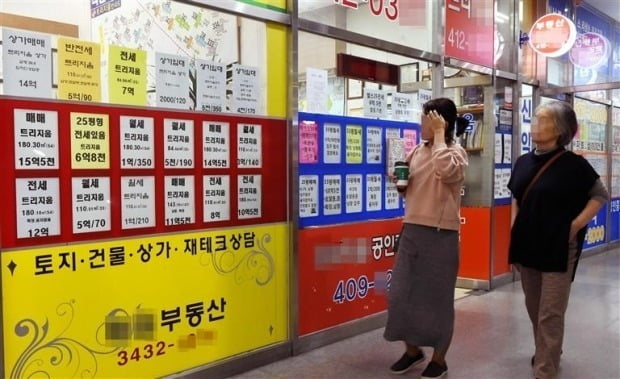 서울 송파구 잠실에서 시민들이 공인중개업소 유리창문에 붙어 있는 매물 관련 정보를 보고 있다. 사진=한경DB