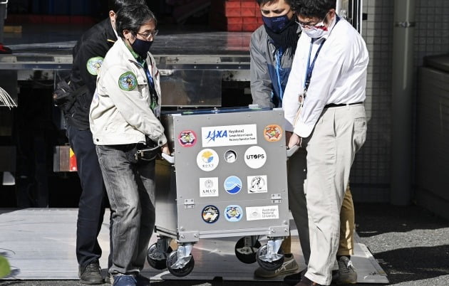 지난해 12월 일본 소행선 탐사선 하야부사2가 채취한 시료 캡슐이 도쿄 인근 일본항공우주개발기구(JAXA) 연구시설에 도착하고 있다. 캡슐에서 소행성 류규에서 채취한 다량의 모래가 확인됐다. /연합뉴스