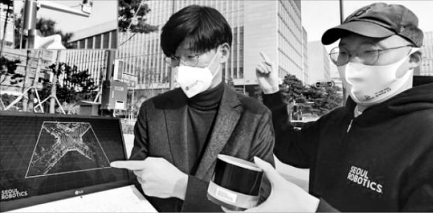 서울 마곡 LG유플러스 사옥 앞 교차로에 설치된 라이다 센서를 주영준 LG유플러스 차세대기술Lab장(왼쪽)과 이한빈 서울로보틱스 대표(오른쪽)가 살펴보고 있다.  LG유플러스  제공 