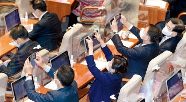 3일 국회에서 더불어민주당 의원들이 휴대폰으로 본회의장을 촬영하고 있다. 이날 여당은 607조7000억원 규모의 내년 예산안을 강행 처리했다. /국회사진기자단 