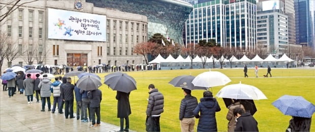 15일 오전 서울광장에 마련된 코로나19 임시선별진료소에서 검사를 받으려는 시민들이 비가 내리는 가운데 길게 줄을 서 있다. 정부는 코로나19 확산세를 차단하기 위해 고강도 거리두기를 조만간 시행할 방침이다.  /허문찬 기자 