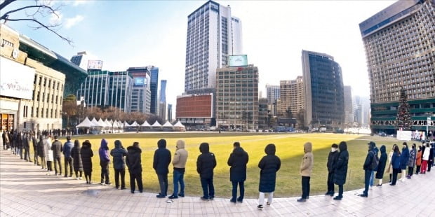 17일 오전 서울시청 앞 선별진료소에서 시민들이 코로나19 검사를 받기 위해 길게 줄 서 있다. 전날 신규 확진자 수는 7435명으로 사흘 연속 7000명대를 기록했다.   김범준 기자 