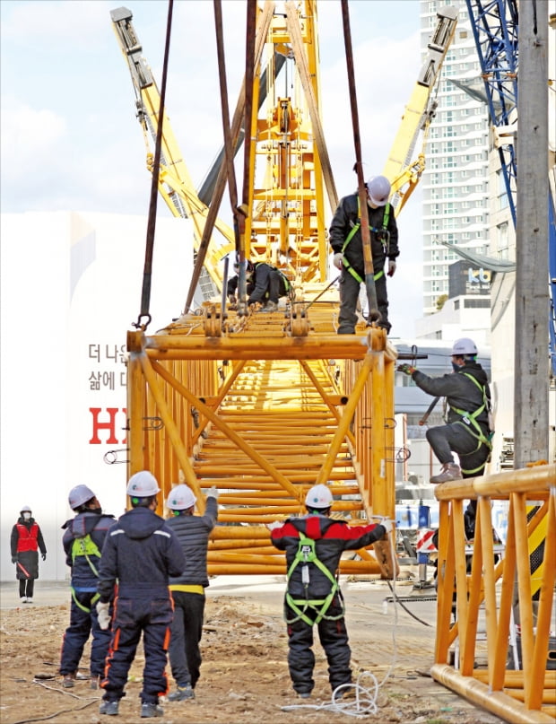 16일 광주 신축 아파트 붕괴사고 현장에서 관계자들이 타워크레인 해체 작업에 투입할 크레인을 조립하고 있다. 기울어진 상태로 아파트 건물과 연결돼 있는 140m 높이의 타워크레인은 붕괴 위험으로 인해 해체 목표 시기가 오는 21일로 미뤄졌다.  연합뉴스 