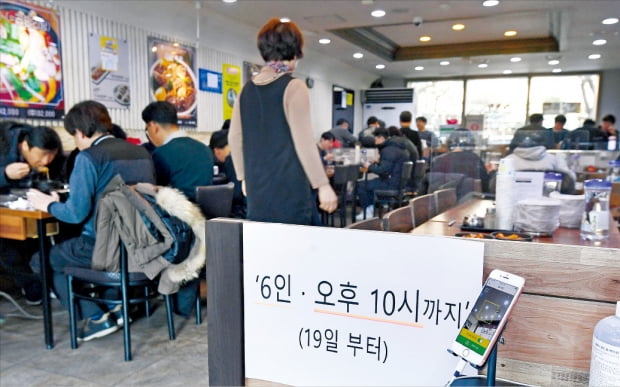 18일 서울 시내 한 음식점 입구에 새로운 거리두기 내용을 알리는 안내문이 붙어 있다. 방역당국은 사적모임 인원수(최대 6명)는 유지하고 식당 카페 등의 영업시간은 밤 9시에서 10시까지로 1시간 늘렸다.  김범준 기자 