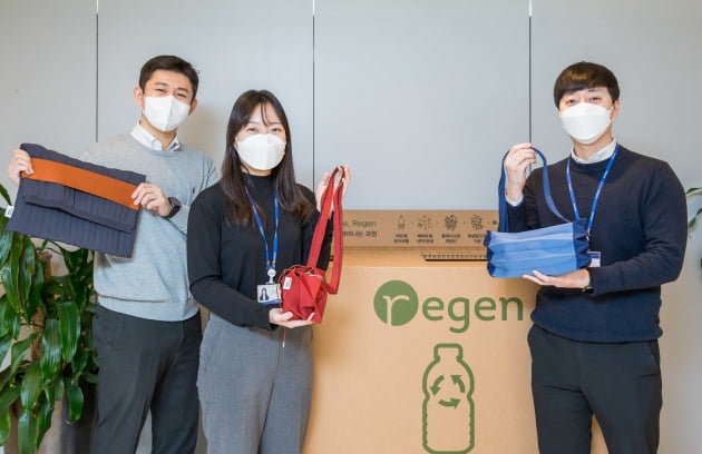 효성티앤씨 직원들이 사내 페트병 수거함 앞에서 친환경 섬유 리젠으로 만든 가방을 선보이고 있다.(사진=효성)