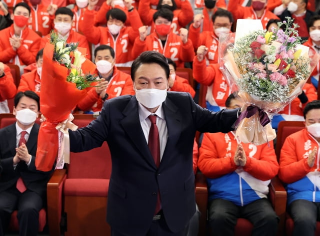 윤석열 대통령 당선인이 10일 새벽 서울 여의도 국회도서관에 마련된 '국민의힘 제20대 대통령선거 개표상황실'을 찾아 꽃다발을 받은 뒤 취재진을 향해 포즈를 취하고 있다. / 사진=연합뉴스