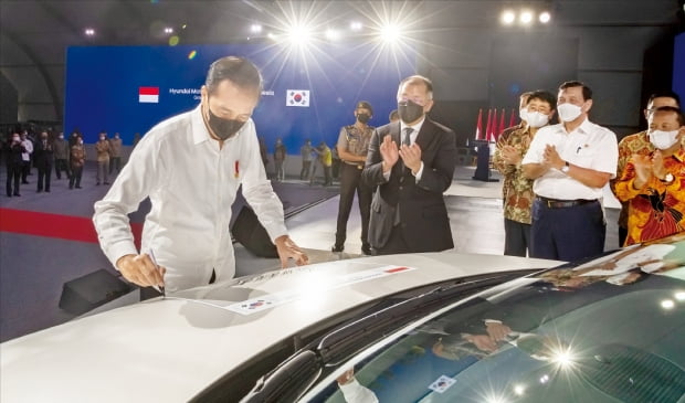 조코 위도도 인도네시아 대통령(왼쪽)이 지난 16일 인도네시아 브카시시의 현대자동차 공장에서 열린 준공 및 수출 기념식에서 정의선 현대차그룹 회장(가운데)이 지켜보는 가운데 전기차 아이오닉 5에 서명하고 있다.  현대차제공
 