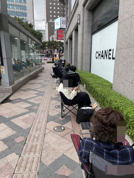 이른 새벽 서울 중구 신세계백화점 본점 샤넬 매장 앞에서 구매 대기자들이 캠핑 의자에 앉아 번호표를 기다리고 있는 모습. 사진=연합뉴스