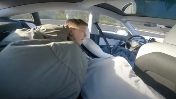 달리는 테슬라 차량 뒷좌석에 눕는 운전자. /사진=유튜브 캡처