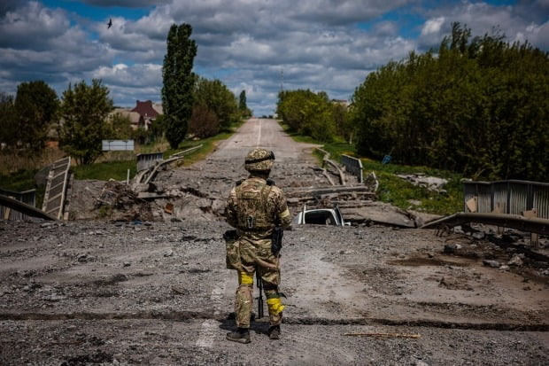 우크라이나 병사가 16일(현지시간) 하르키우(하리코프) 북쪽 루스카 로조바 마을 인근의 파괴된 다리 앞에서 경계근무를 서고 있다. /연합뉴스