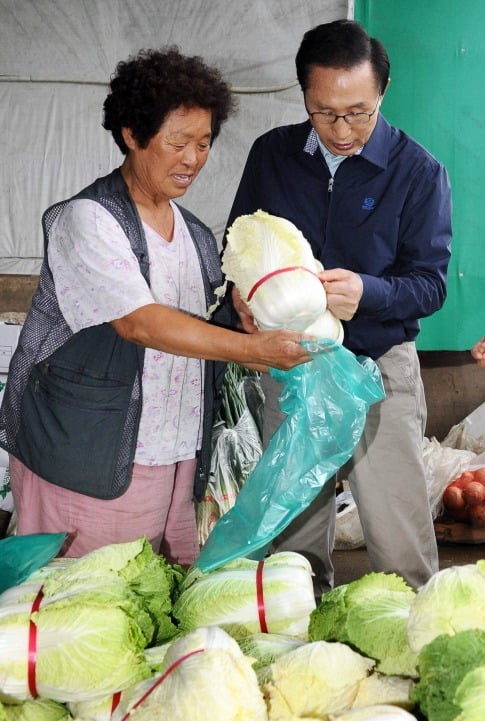  2010년 구리농수산물도매시장을 방문한 이명박 전 대통령이 한 가게를 찾아 상인을 격려한 후 배추를 구매하고 있다. 사진=한경DB