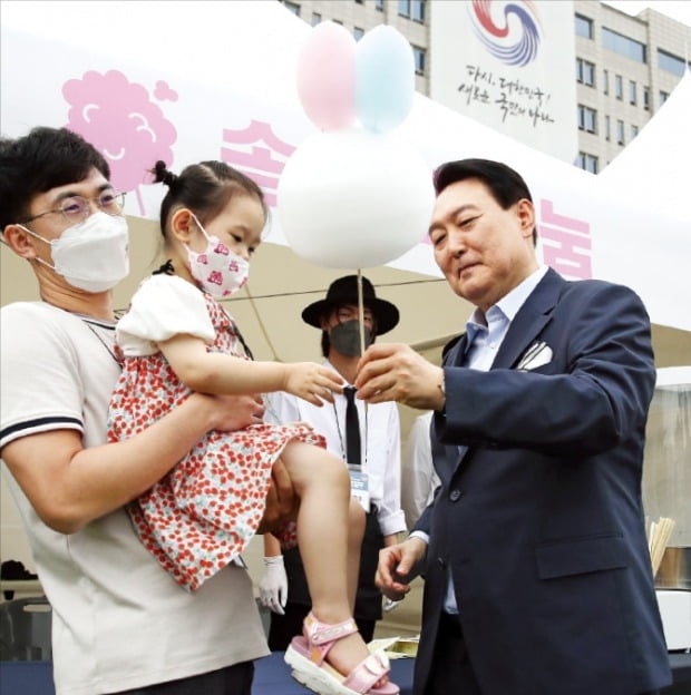 윤석열 대통령이 19일 용산 대통령실 앞 잔디마당에서 열린 ‘대통령실 이전 기념 주민 초대 행사’에서 어린이에게 토끼 모양의 솜사탕을 주고 있다.  김범준  기자 