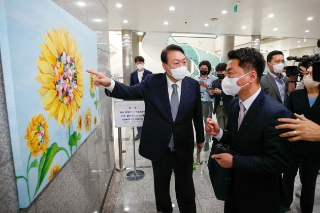 윤석열 대통령이 25일 용산 대통령실 로비에서 발달장애 화가 강선아씨의 작품 《해바라기2》를 가리키면서 대화하고 있다. 대통령실사진기자단