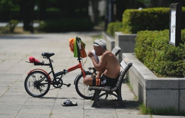 일본 도쿄의 한 공원에서 자전거 운전자가 폭염 속에 휴식을 취하며 얼굴의 땀을 닦아내고 있다. /사진=AP