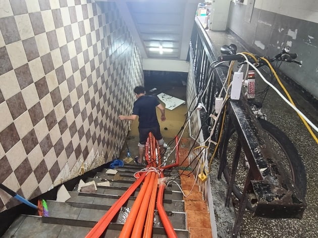 9일 서울 동작구 남성사계시장 한 상인이 빗물을 빼고 있는 모습.