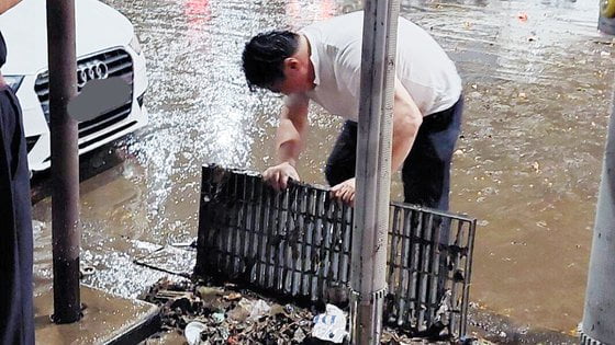 서울 남부에 시간당 100mm 폭우가 쏟아진 가운데, 서울 강남역 인근에서 한 남성이 맨손으로 막힌 배수로를 뚫고 있다. / 사진=온라인 커뮤니티